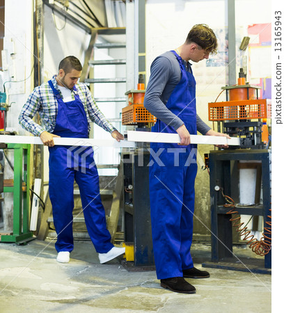 Two workers working on a machine Two workers working on a machine 13165943