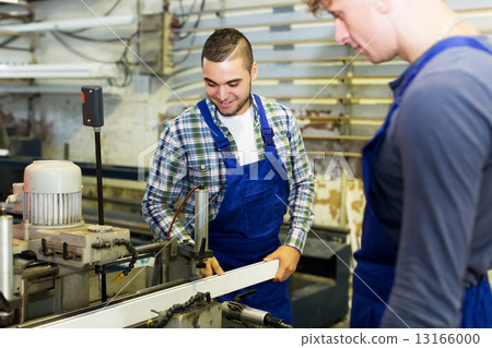Two workers working on a machine 13166000