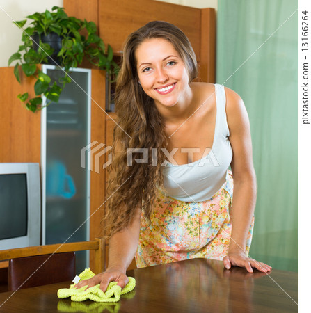 young woman dusting wooden table 13166264