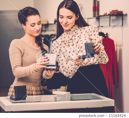 Young woman choosing jewellery with shop assistant help Young woman choosing jewellery with shop assistant help 13168426