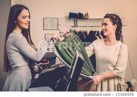 Happy woman customer paying in fashion showroom Happy woman customer paying in fashion showroom 13168430
