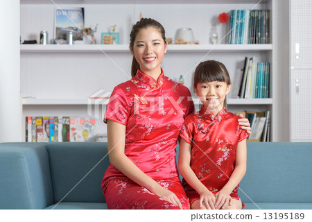 Young chinese mother and daughter in cheongsam sitting together in the living room Young chinese mother and daughter in cheongsam sitting together in the living room 13195189