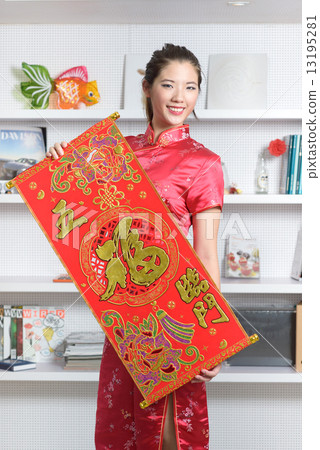 One young Chinese woman in cheongsam holding 5 good fortunes red banner in front of bookshelf 13195281