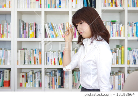 在圓珠筆和書架前面的女性白色女襯衫 13198664