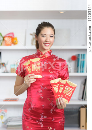 Young Chinese woman in cheongsam holding 5 red packets in a fan shape in front of bookshelf Young Chinese woman in cheongsam holding 5 red packets in a fan shape in front of bookshelf 13205544