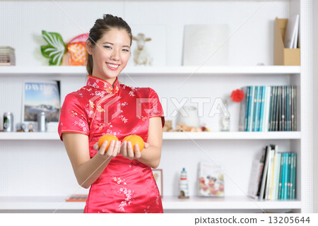 Young chinese woman in cheongsam holding oranges in front of bookshelf Young chinese woman in cheongsam holding oranges in front of bookshelf 13205644
