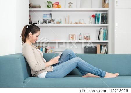 One young chinese woman using mobile device tablet iPad relaxing on a sofa 13218636