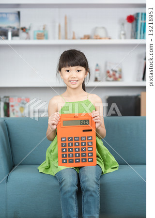 Young chinese girl sitting on a sofa using a big calculator  13218951