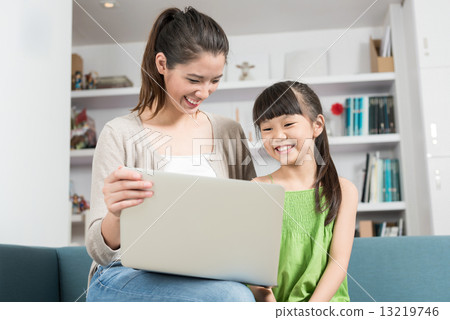 Young chinese mother and daughter using mobile device laptop at home 13219746