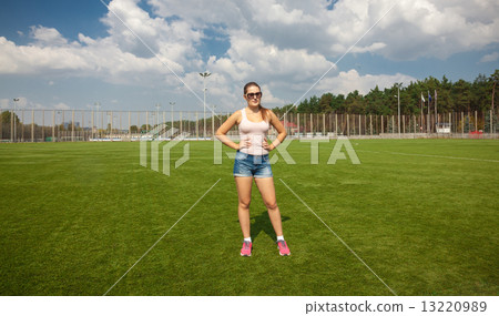 slim woman standing on soccer field at sunny day 13220989