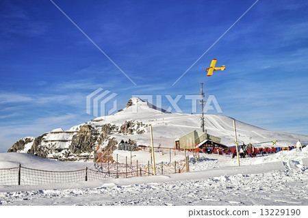 Yellow airplane flying over alpine resort in swiss alps in winte 13229190