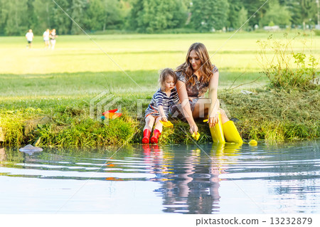 Adorable little girl and her mom playing with paper boats in a r 13232879