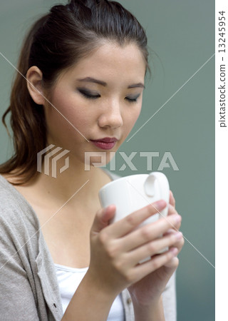 One young chinese woman holding a cup of hot coffee 13245954