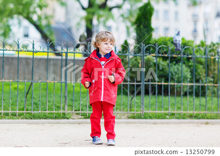 Cute little  boy catching and playing with pigeons in city 13250799