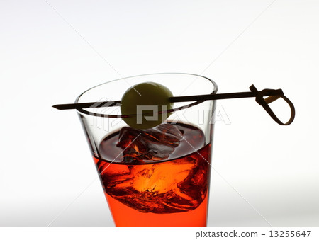 Short drink glass with red liquid, olive, ice cubes 13255647