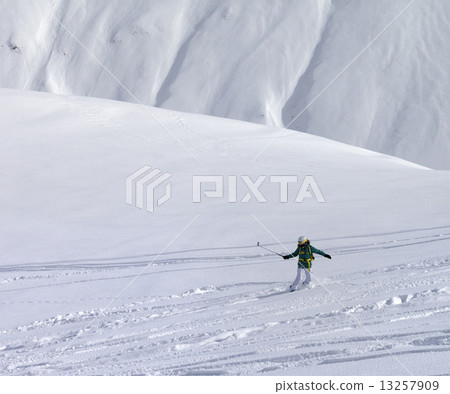 Snowboarder downhill on off piste slope with newly fallen snow 13257909
