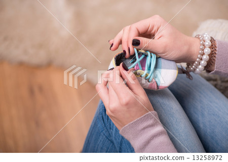 Young attractive woman holding baby shoe, interior shot 13258972