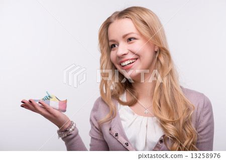 Young attractive woman holding baby shoe isolated on white backg Young attractive woman holding baby shoe isolated on white backg 13258976