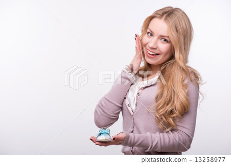 Young attractive woman holding baby shoe isolated on white backg Young attractive woman holding baby shoe isolated on white backg 13258977