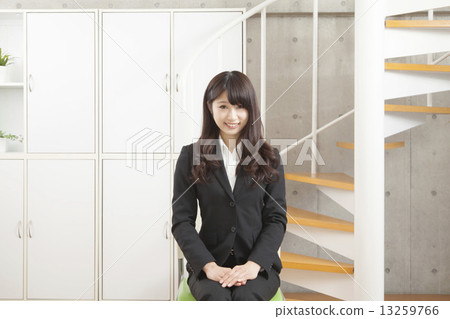 A woman in a suit sitting in front of the stairs 13259766