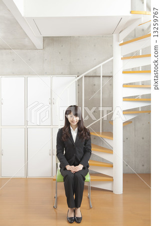 A woman in a suit sitting in front of the stairs 13259767