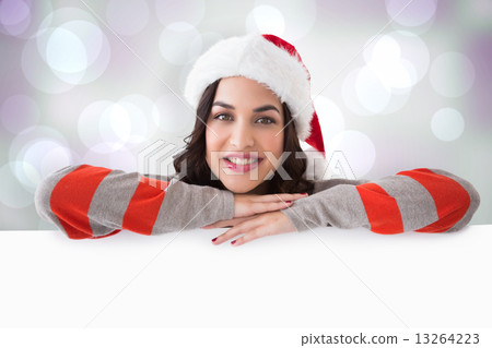 Composite image of beauty brunette in santa hat smiling at camer 13264223