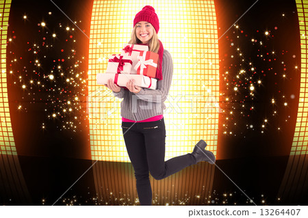 Composite image of festive blonde holding pile of gifts 13264407