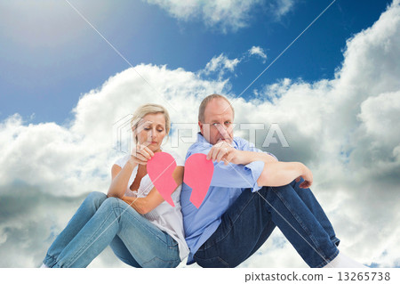 Composite image of sad mature couple holding a broken heart 13265738