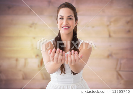 Composite image of smiling brunette holding hands out 13265740