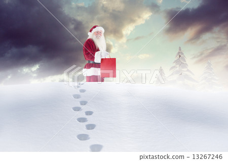 Composite image of santa carrying gifts in the snow 13267246