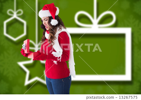 Composite image of disgusted brunette opening christmas gift 13267575