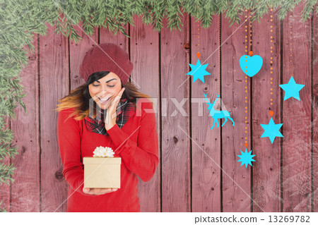 Composite image of surprised brunette holding a gift Composite image of surprised brunette holding a gift 13269782