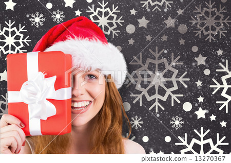 Composite image of festive redhead holding a gift 13270367