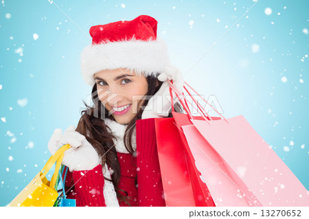 Composite image of festive brunette in winter wear holding shopp 13270652