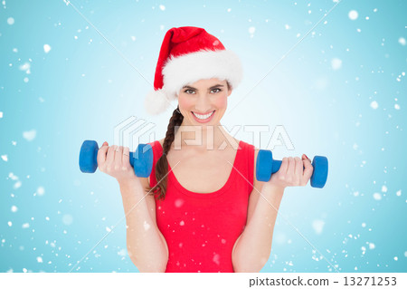 Composite image of festive fit brunette holding dumbbells 13271253