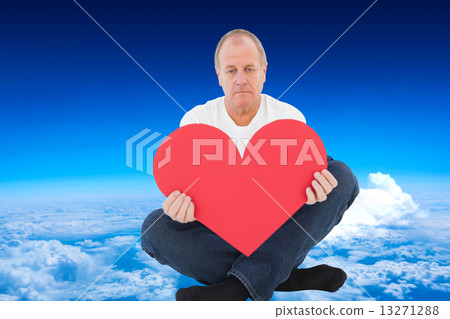 Composite image of upset man sitting holding heart shape Composite image of upset man sitting holding heart shape 13271288
