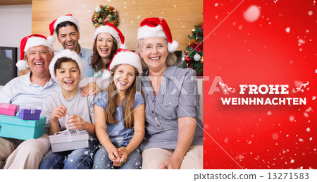 Composite image of extended family in christmas hats with gift b 13271583