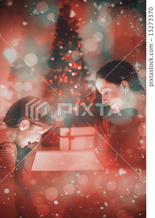 Composite image of festive mother and daughter opening a glowing Composite image of festive mother and daughter opening a glowing 13273370