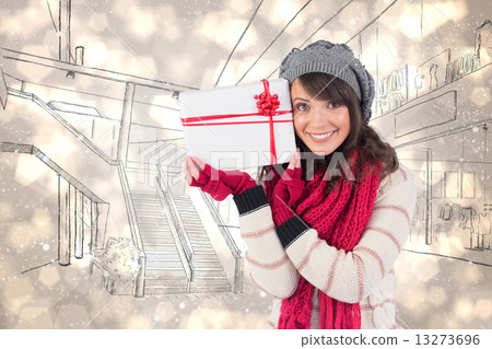Composite image of festive brunette holding white and red gift 13273696