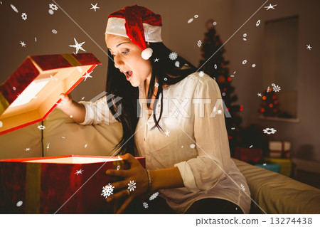 Composite image of festive brunette opening a glowing christmas Composite image of festive brunette opening a glowing christmas 13274438
