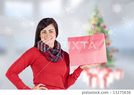 Composite image of smiling brunette showing red gift bag 13275636
