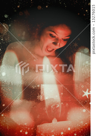 Composite image of pretty brunette in santa outfit opening gift 13276015