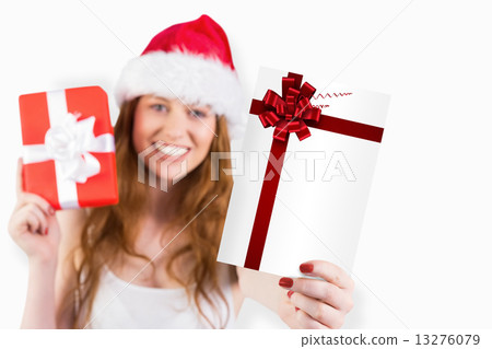 Composite image of festive redhead holding a gift Composite image of festive redhead holding a gift 13276079
