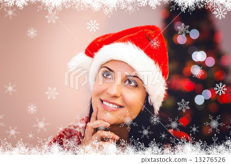 Composite image of festive brunette wearing a santa hat 13276526