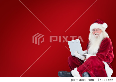 Composite image of santa sits and uses a laptop Composite image of santa sits and uses a laptop 13277366