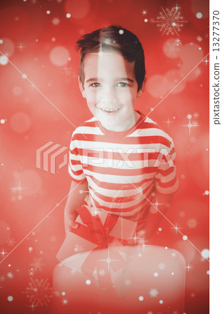 Composite image of festive little boy holding a gift 13277370