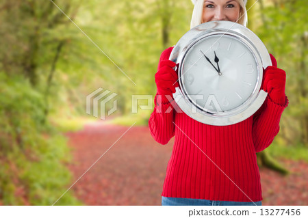 Composite image of happy festive blonde with clock 13277456
