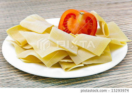 Macaroni products - a basis for a lasagna, with a tomato on a plate Macaroni products - a basis for a lasagna, with a tomato on a plate 13293974