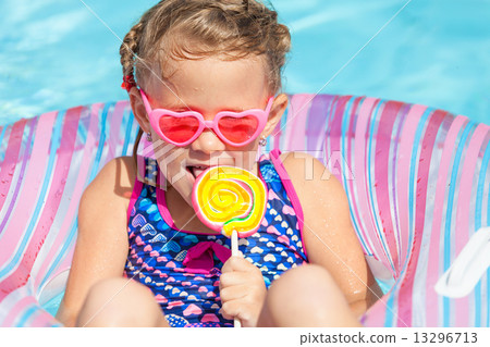 little girl with lollipop lying on the  inflatable rubber circle 13296713