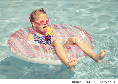 little girl with lollipop lying on the inflatable rubber circle little girl with lollipop lying on the inflatable rubber circle 13296714